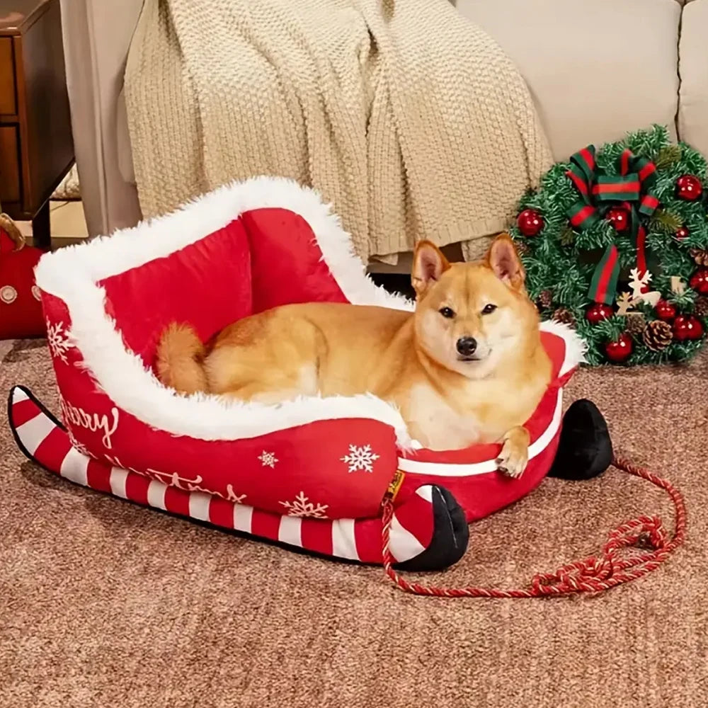 Dog lying in a red Christmas-themed dog bed with a small Christmas tree in the background.